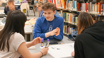 three students sitting at a library table
