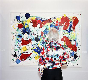 Martin Parr stands facing a painting