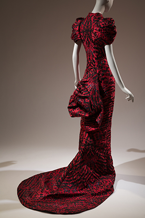 Floor-length red dress with black pattern shown from back with bustle and train