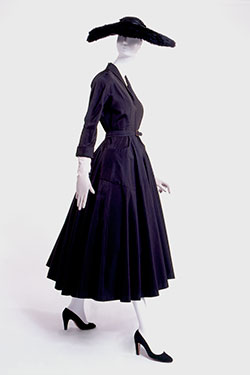 black dress with small shawl collar, 3/4 length kimono sleeves, ankle-length flared circle skirt, rounded patch pockets, matching contour belt, and horsehair petticoat