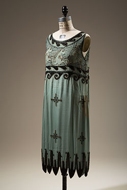short turquoise beaded dress with open low round neckline, black jet and gold seed beads hand sewn on bodice in scroll and horse with ristowe button eye design