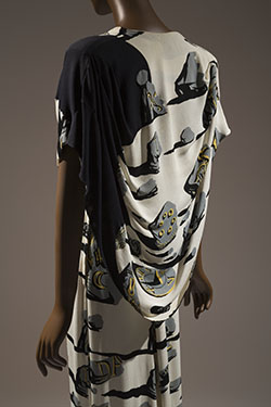 long evening dress in ivory rayon crinkly crepe printed with surrealist design of gray shattered monument stones with black shadows and yellow ancient incriptions
