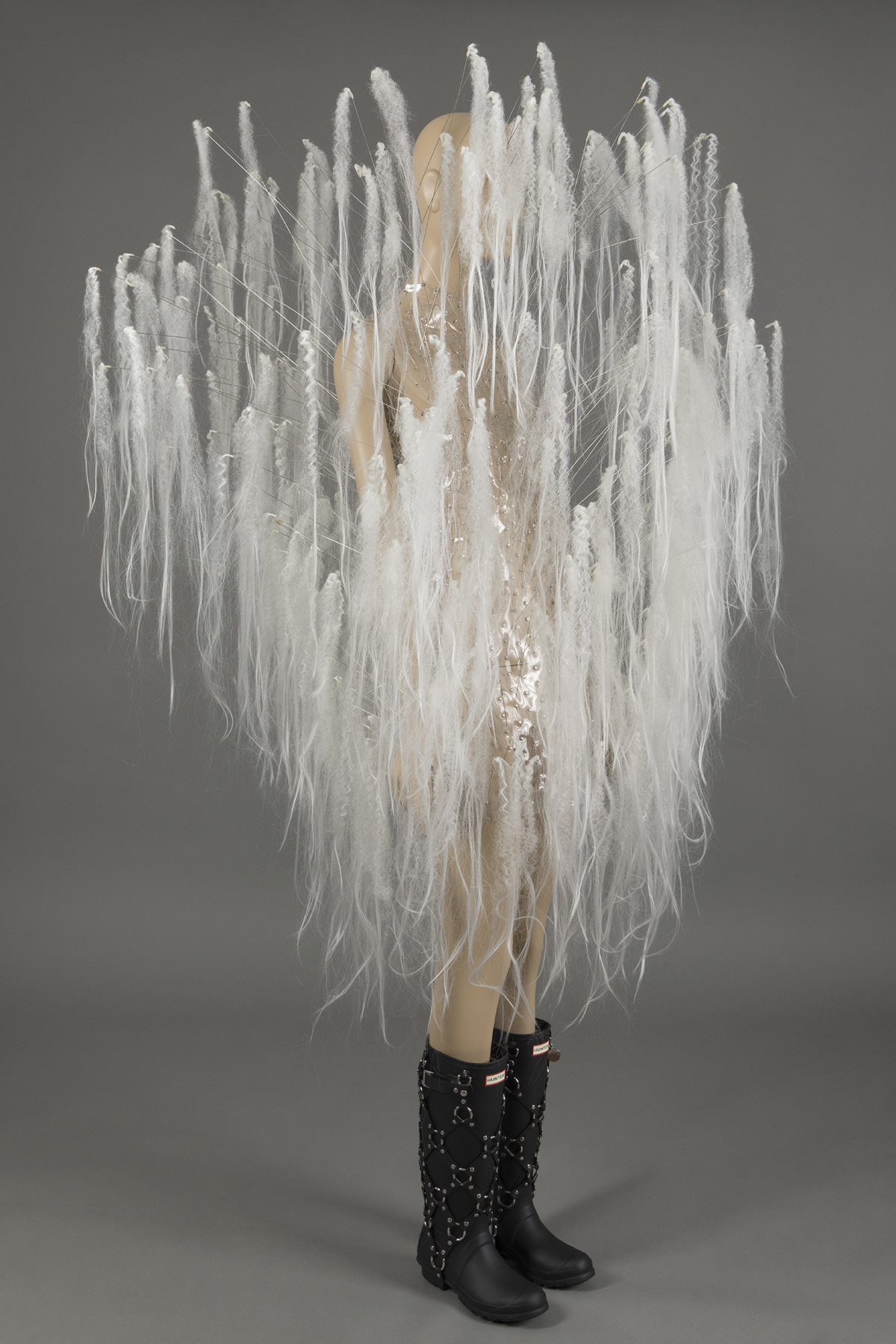 Dress made of clear polyurethane with protruding stainless-steel rods with white synthetic hair extensions; black rain boots by Hunter,
