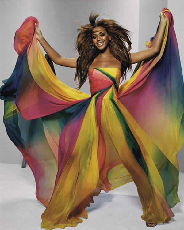 beyonce with arms spread wearing long rainbow-colored dress