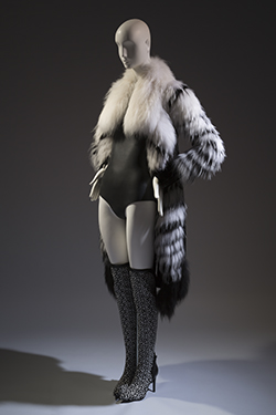 long haired black and white fur coat, black shearling at side front and back oanels, black leather at under sleeves and wide collar in white fur with black sharkskin neoprene sleeveless bodysuit underneath and black and white stretch knit above the knee boots