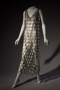 Long chain mail dress of white, pearlescent and silver plastic rectangles linked by metal loops; sleeveless, deep square front neck