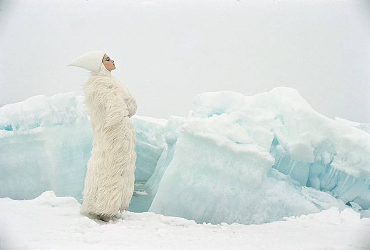 1964 image of woman in white fur standing amidst glaciers in the arctic
