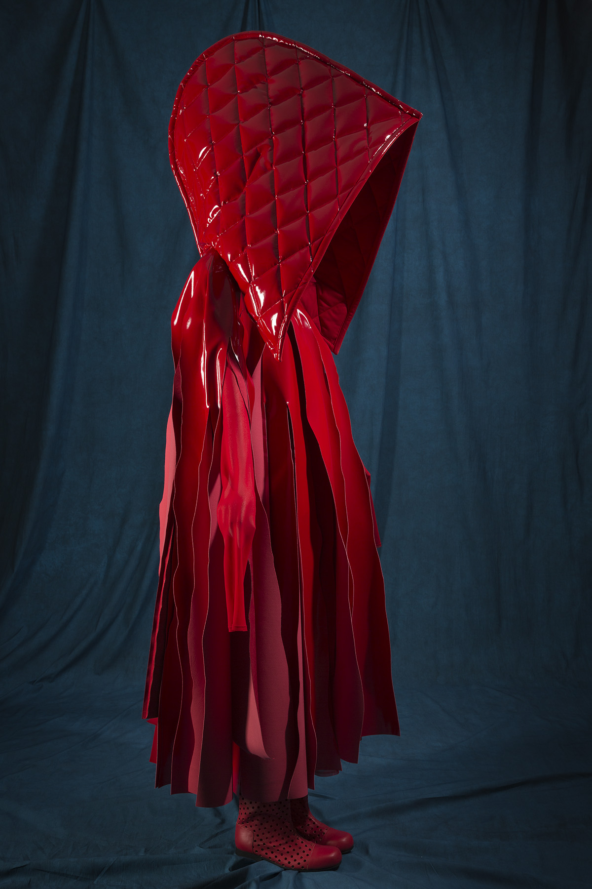 red ensemble with oversized detachable hood and cape with streamer-like panels cut from upper bodice to hem