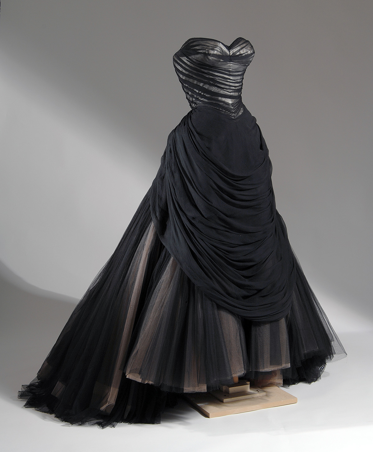 strapless black ballgown with sweeping trained full skirt with layers of black, beige, and brown net gathered into back bustle roll
