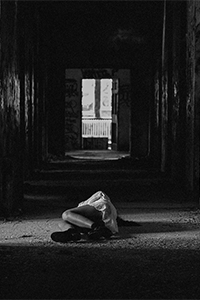 Black and white photo of woman lying on ground in abandoned building