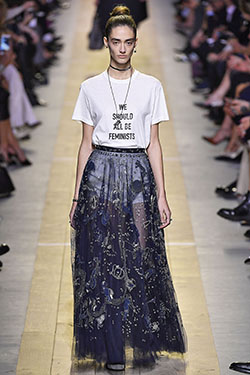 model walking down runway in sheer blue embroidered and embellished skirt and white t-shirt that read 'We Should All Be Feminists'
