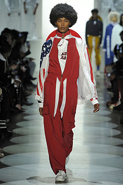 model walking down runway wearing a red jumpsuit with the American flag on sleeves