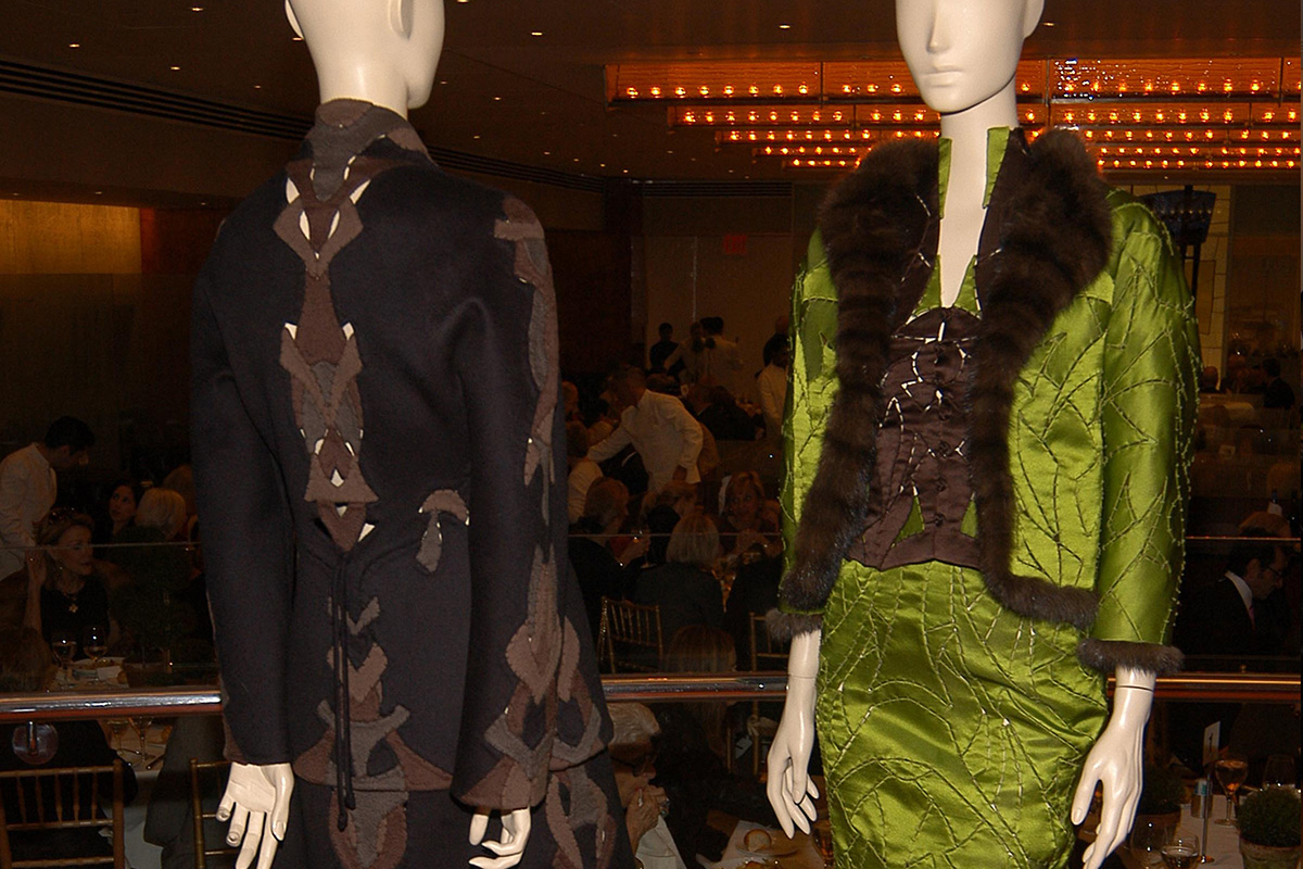 two mannequins in Rucci's designs, with people dining in the backround