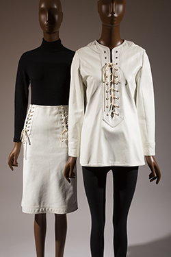 two mannequins: (l)long sleeve black shirt with white leather laced skirt (r) white leather laced tunic