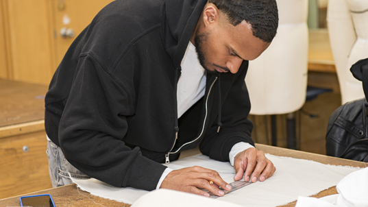 A student measuring for a pattern