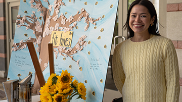 A female student standing next to her artwork for Earth Week