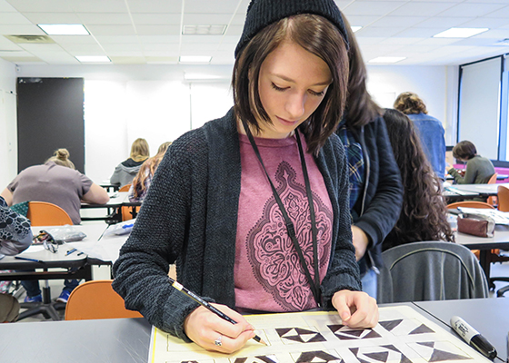 student drawing on a page that contains a number of patterned squares