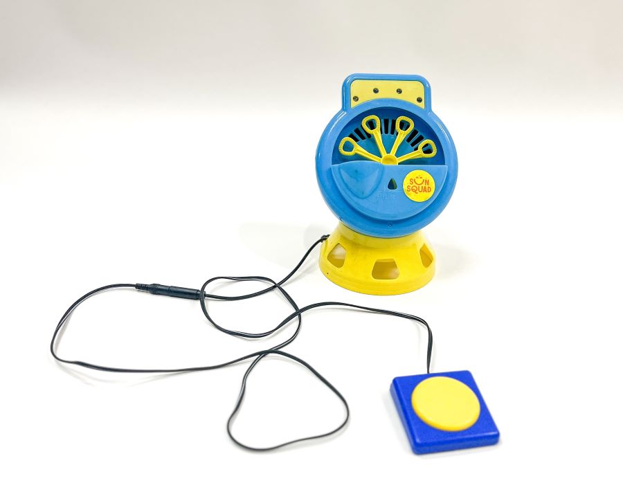 Blue and yellow bubble machine with a connected black wire leading to a large blue switch with a yellow button.