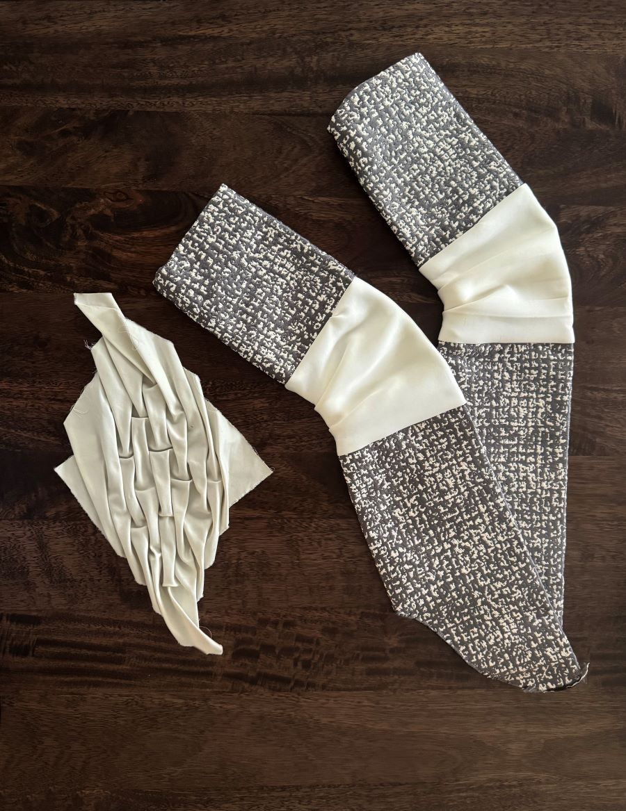 Two gray and white sleeves constructed with accordion pleats on the elbow to demonstrate the flexibility for seated users. The diamond pleat design is another exploration of possible pleats for the elbow and arms.