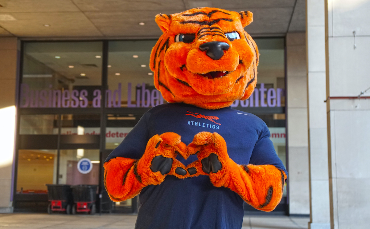 FIT's mascot, Stitch, makes a heart with his paws.