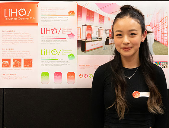 A student standing with her project displayed on easels