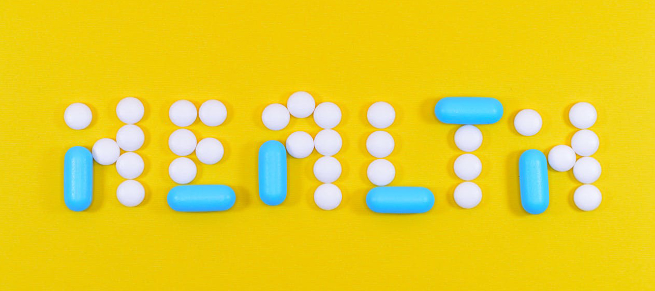 Photograph of pills laid out in a formation that spells "health"