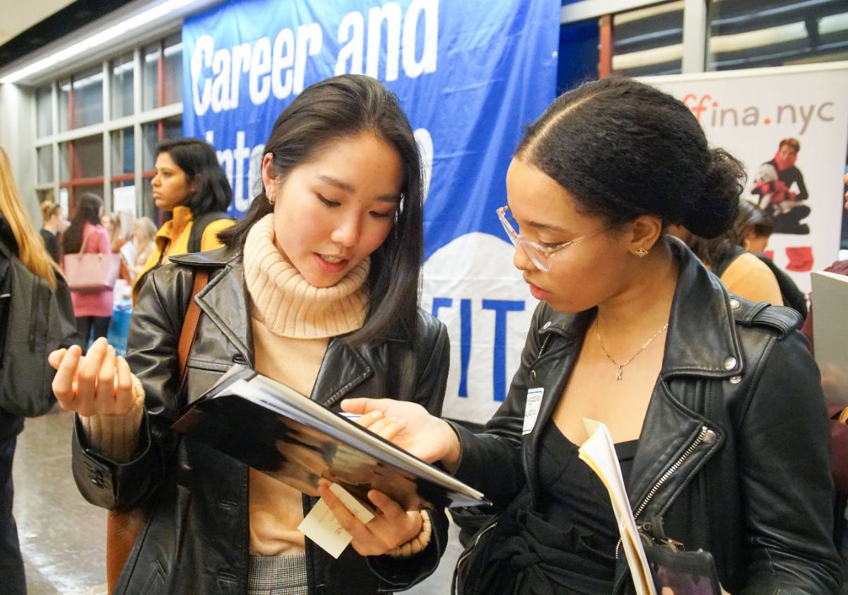 two students reading and discussing a pamphlet at a career and internship fair