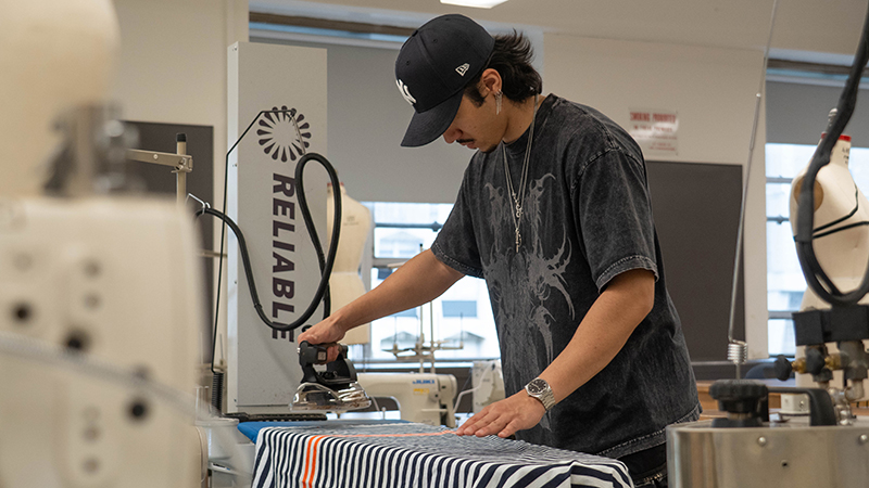a student ironing fabric in class