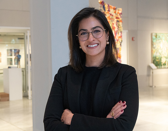 Student wearing a blazer is standing with arms crossed
