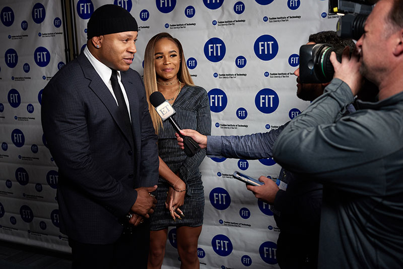 LL Cool J standing with daughter in front of a step and repeat with photographers taking photos