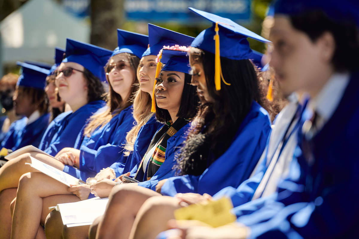 students in regalia sitting in a row at commencement