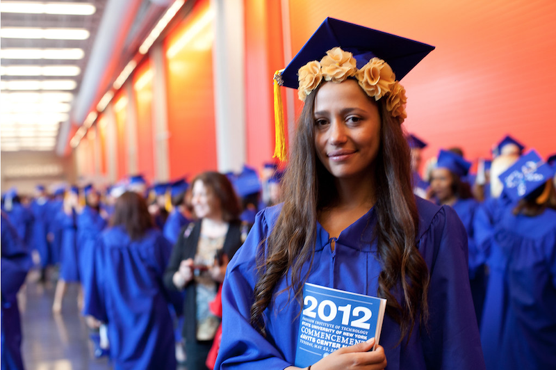 student in blue cap and gown holding 2012 commencent program