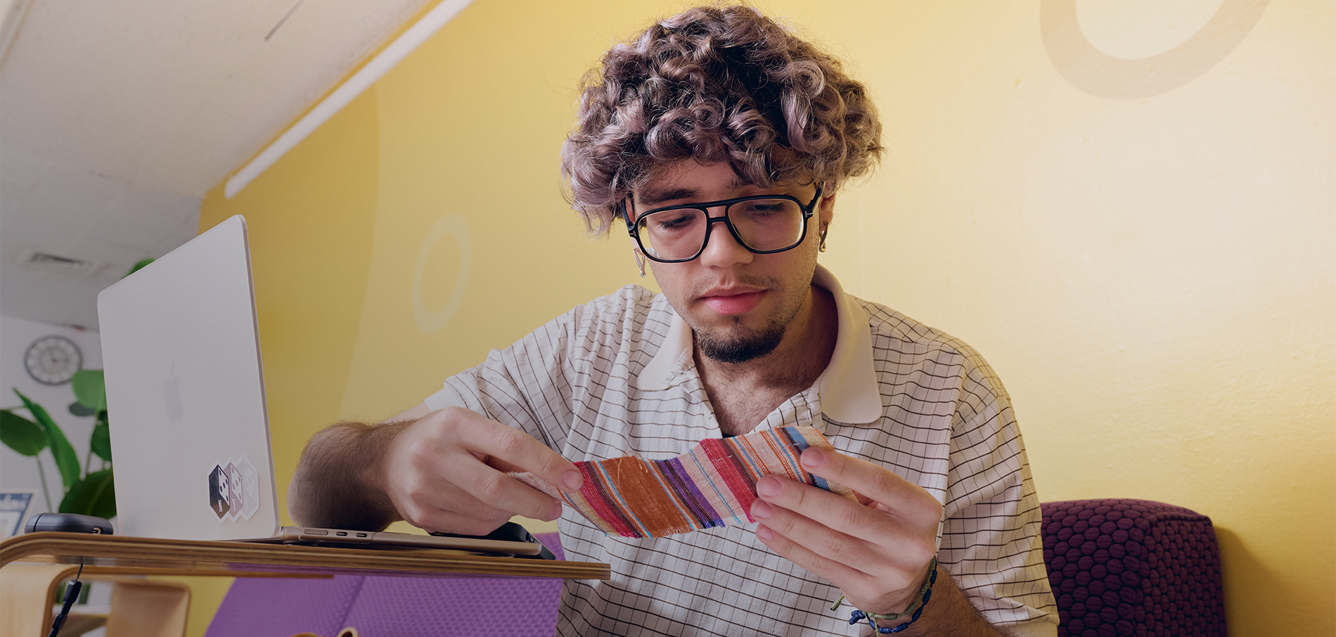 FIT student looking at swatch sitting in front of a laptop