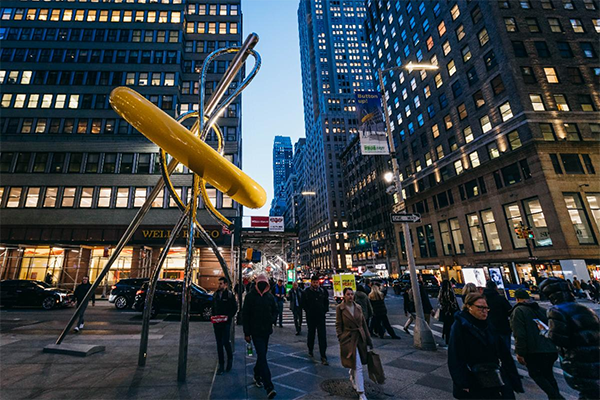 A nighttime photo of the giant button and needle on 7th Avenue