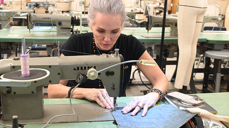 woman seated at a sewing machine working on a garment