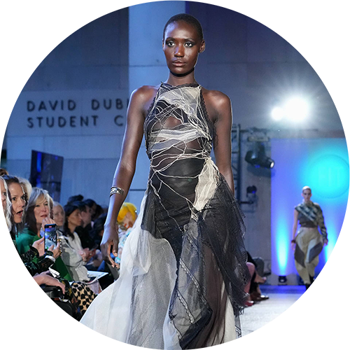 A model walking down the runway in a silver sleeveless dress