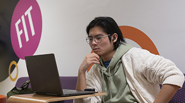 student at FIT looking at laptop