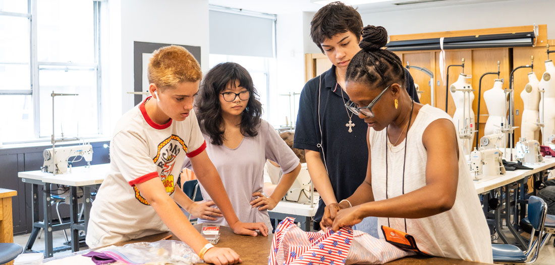 Students standing around a table observing a student's garment they are working on.