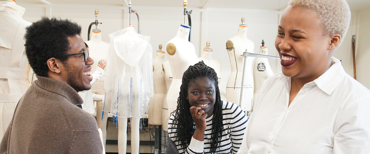 3 FIT BIPOC students laughing together in classroom with dressforms in the background