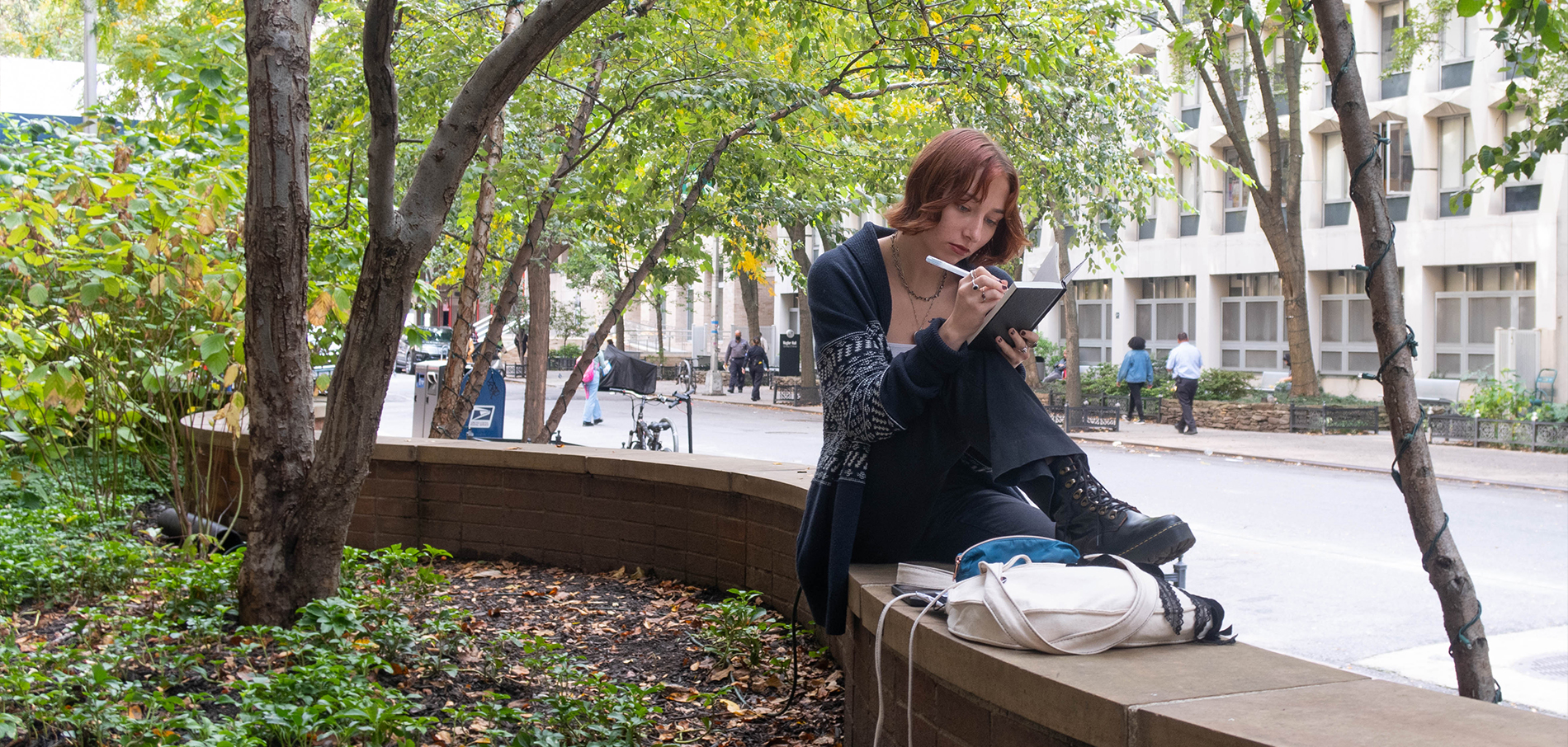 FIT student sitting outdoors writing in notebook