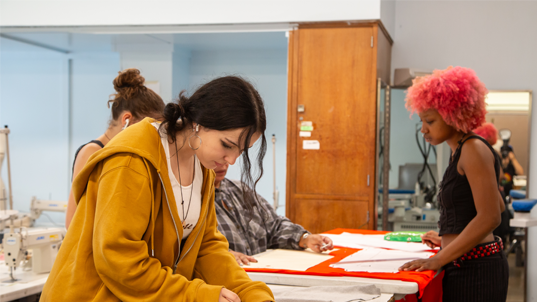 Two students working at designing a garment at a workstation