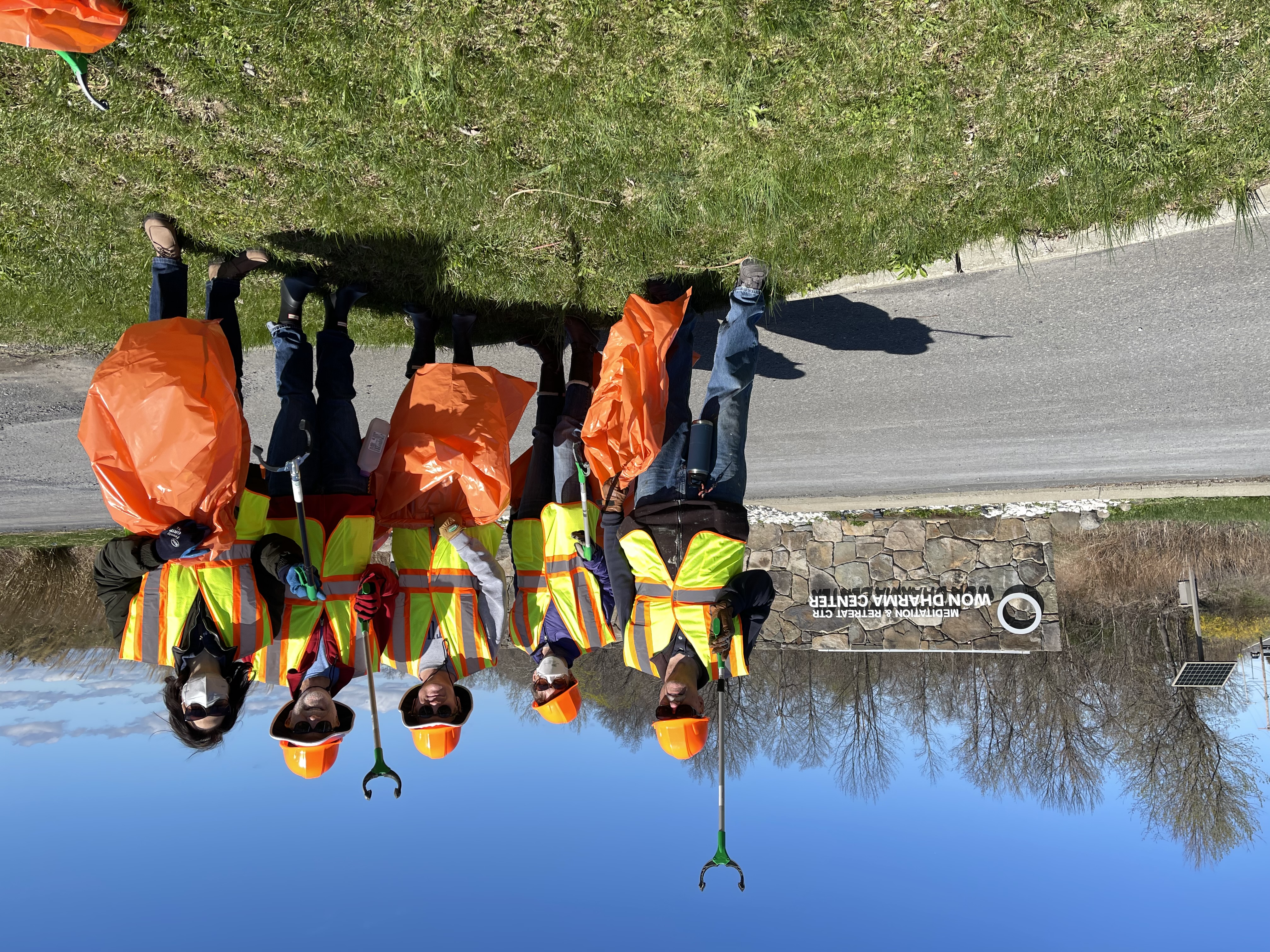 volunteers wearing reflective vests and holding trash bags