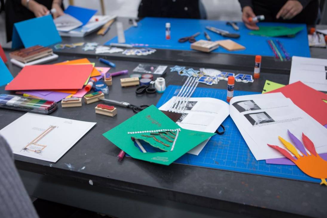 greeting card making event in makerminds space with people around the table strewned with supplies