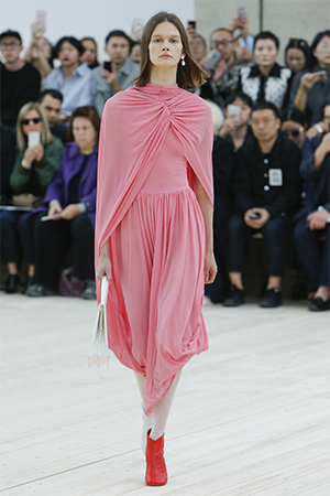 Light pink jersey dress with cape on model on runway