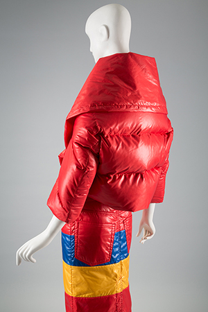 Red puffy parka over blue, yellow, and red striped dress