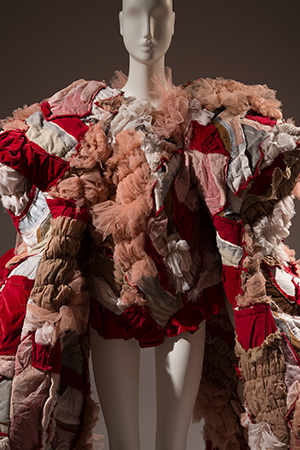 exaggerated "puffy" coat made from patches of pink and red qulted fabric scraps and tulle