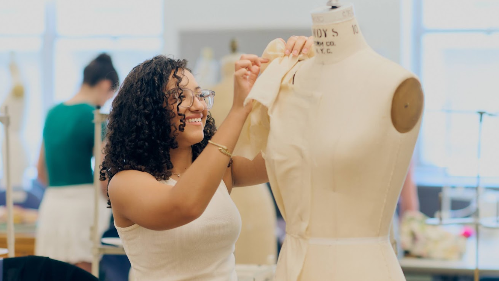 A female high school student pinning muslin on a dress form