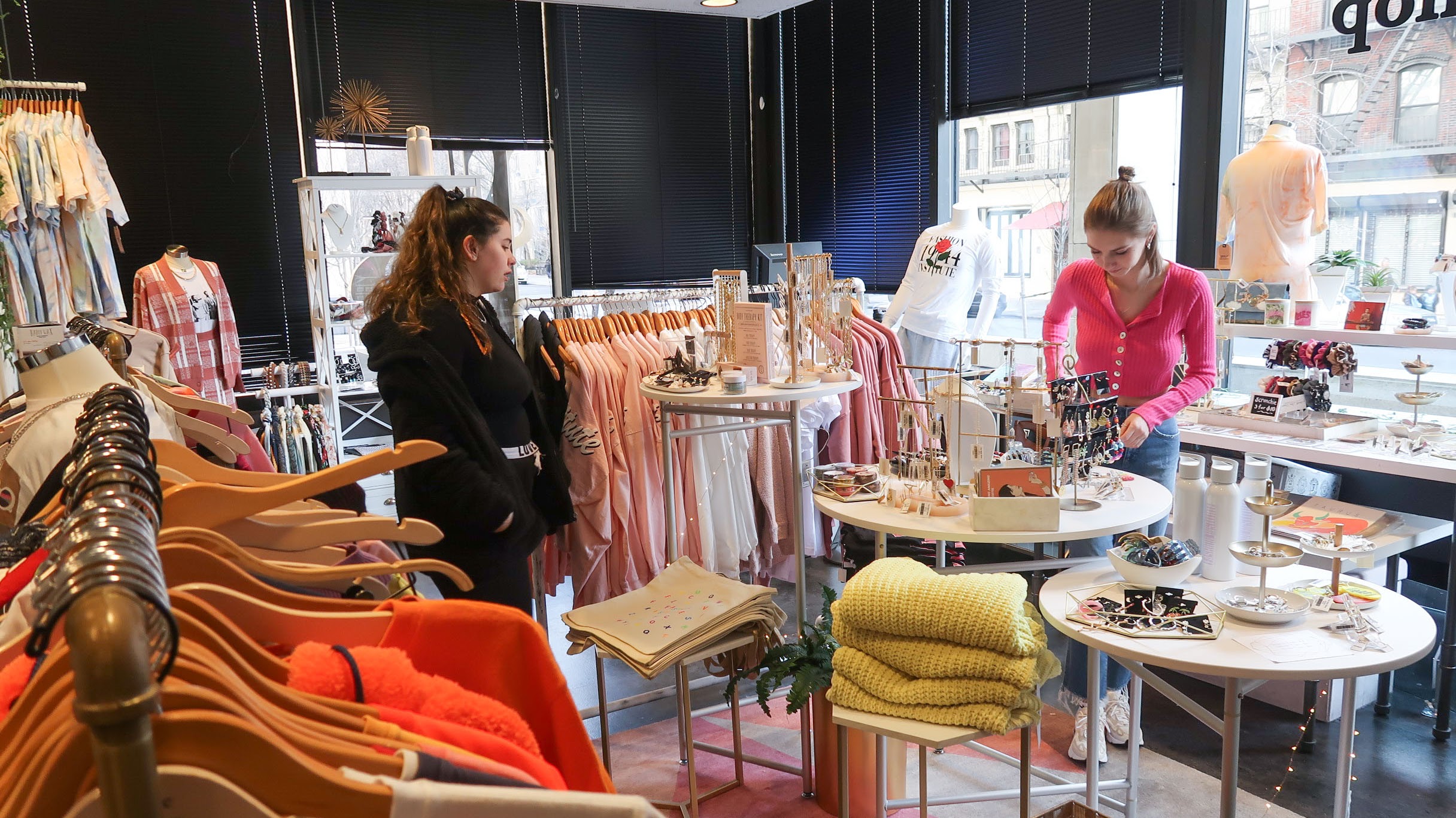 two members of the merchandising society inside the style shop, surrounded by clothing and jewelry