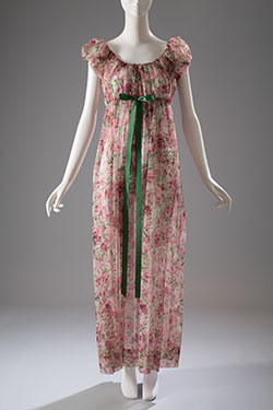 printed gown with floral designs in pinks, greens, and black with deep scoop neck, cap sleeves, and ribbon drawstring for empire bodice