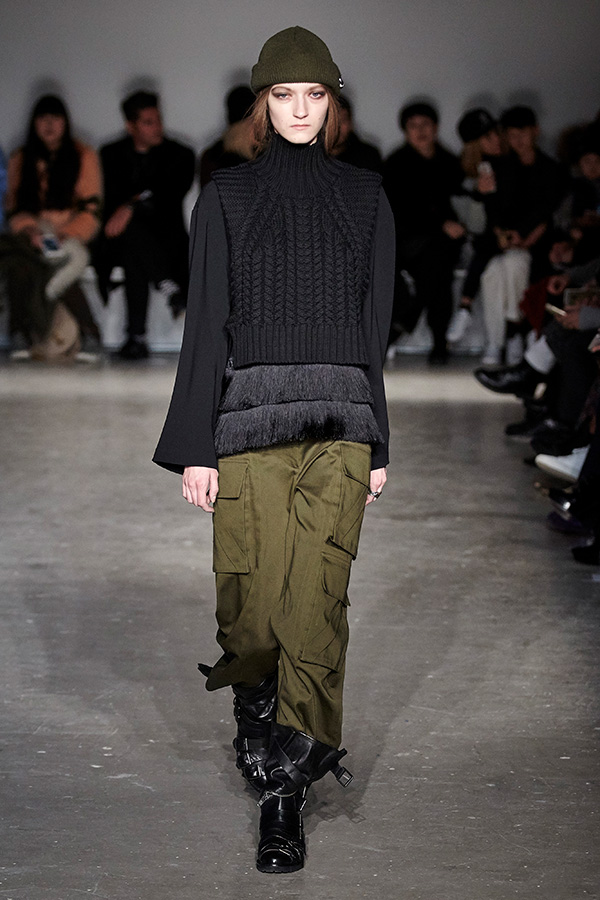 runway image of model wearing green cargo pants with black sweater ensemble